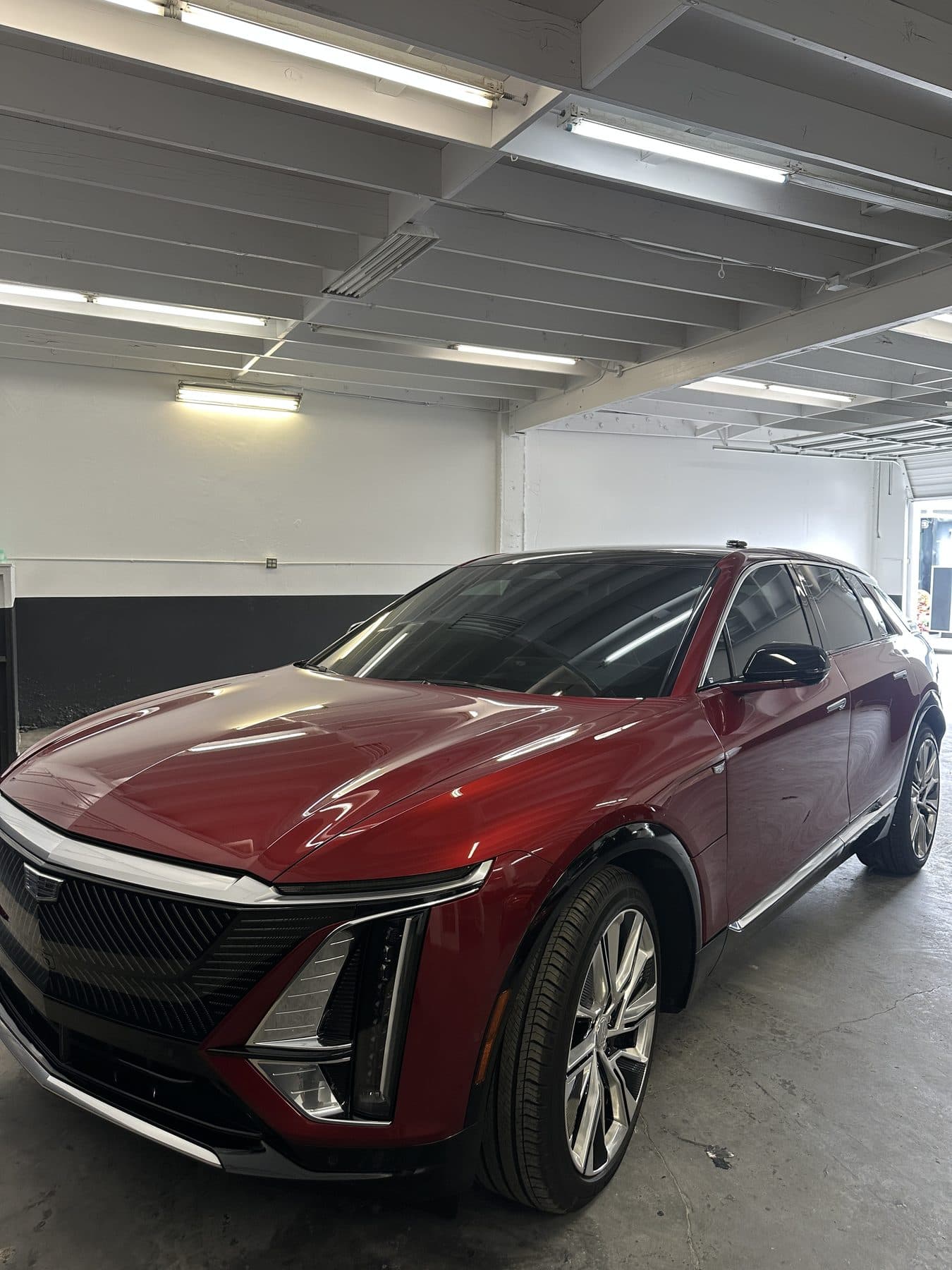 Red Cadillac Lyriq, front three-quarter view in the shop